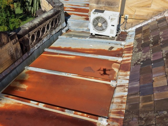 Corroded batten roll panels adjacent to slate